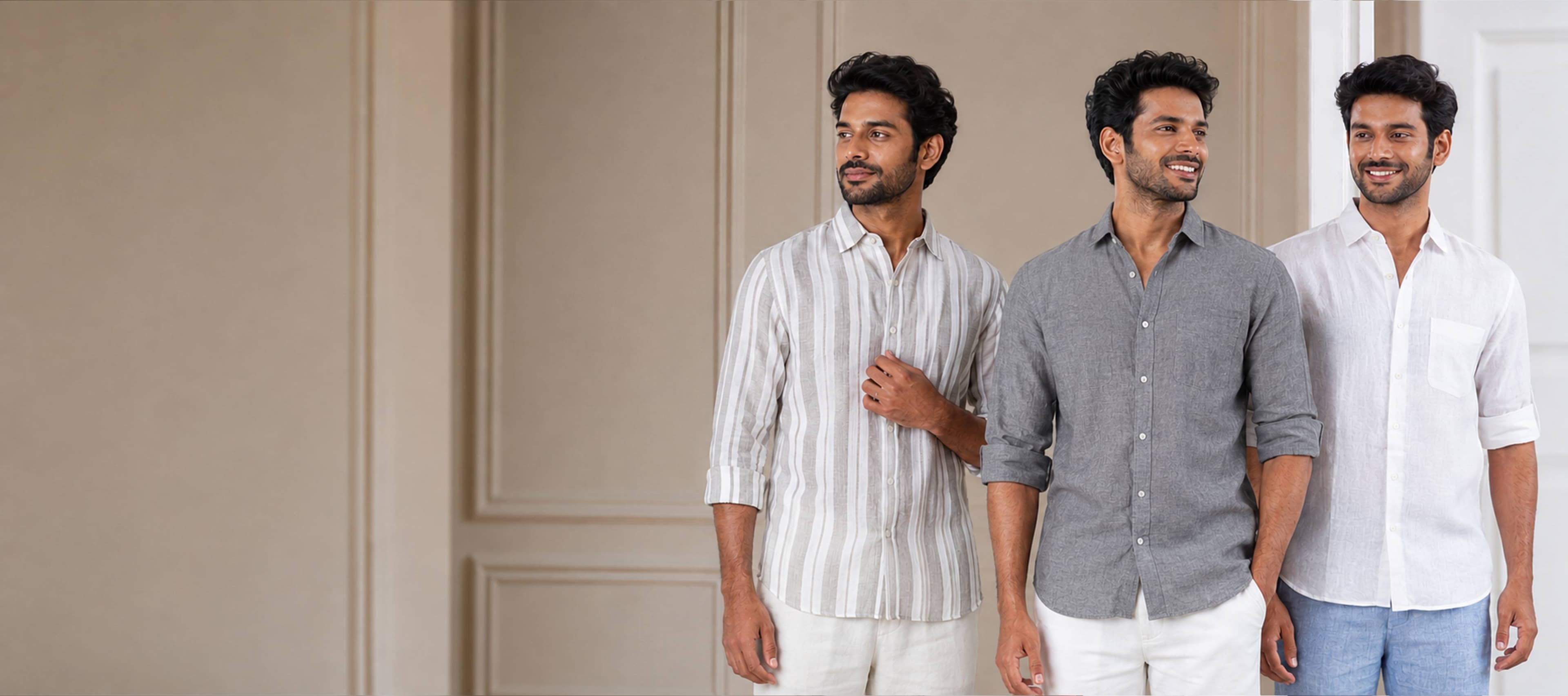 Three men in linen shirts — striped, grey and white — standing against a warm plaster wall